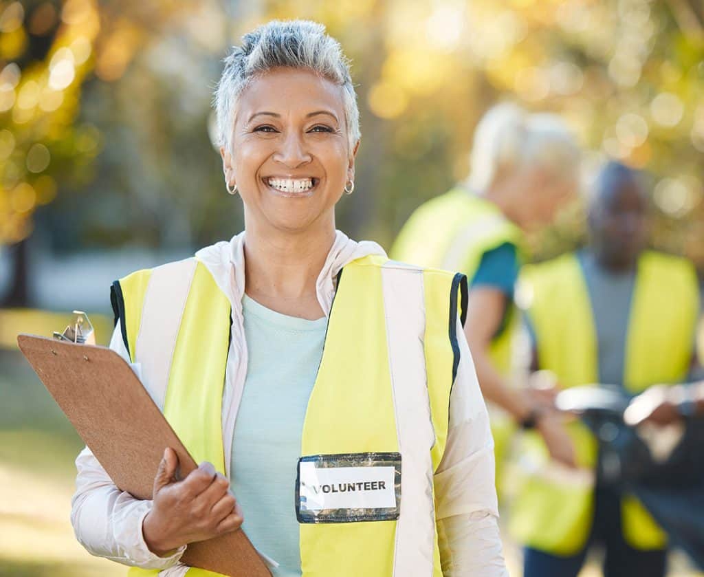 woman wearing a yellow vest with volunteer badge and clipboard